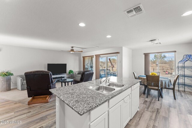 kitchen featuring dishwasher, a kitchen island with sink, white cabinets, ceiling fan, and sink