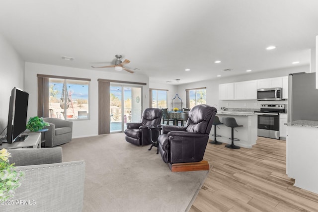 living room with ceiling fan and light hardwood / wood-style flooring