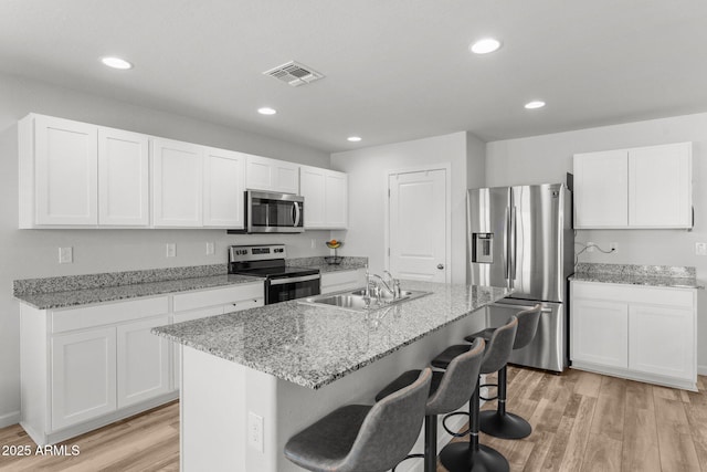 kitchen with stainless steel appliances, a center island with sink, white cabinets, and sink