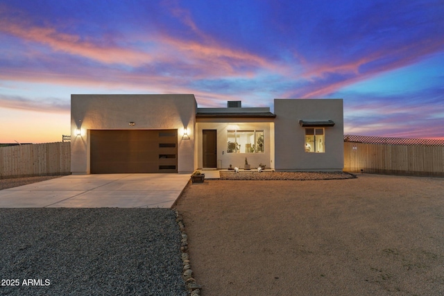 southwest-style home with concrete driveway, stucco siding, fence, and an attached garage