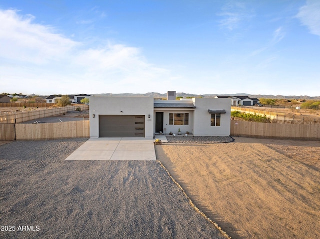 view of front facade featuring fence, a garage, driveway, and stucco siding