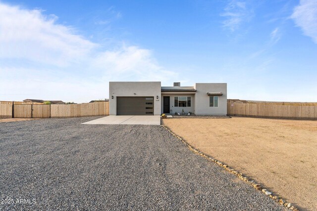 view of front of property with driveway, stucco siding, fence, and an attached garage
