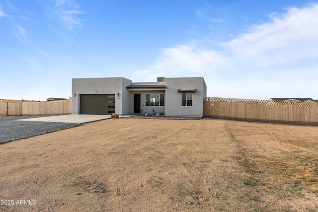 view of front of house featuring concrete driveway, stucco siding, fence, and an attached garage