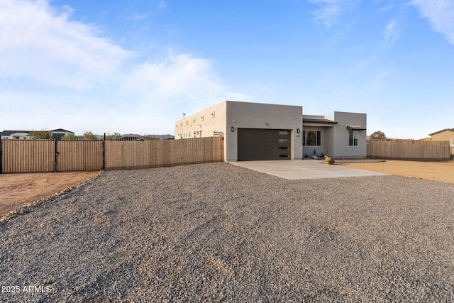 exterior space featuring stucco siding, fence, a gate, an attached garage, and concrete driveway
