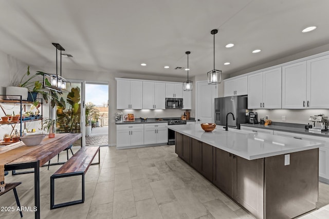 kitchen with white cabinetry, a kitchen island with sink, stainless steel appliances, pendant lighting, and a sink
