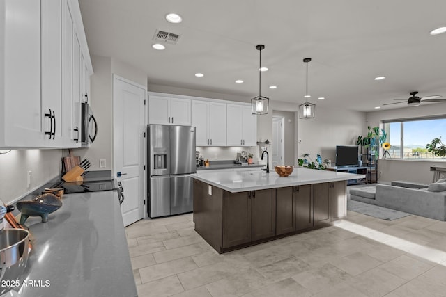 kitchen with visible vents, stainless steel fridge, open floor plan, black microwave, and white cabinetry