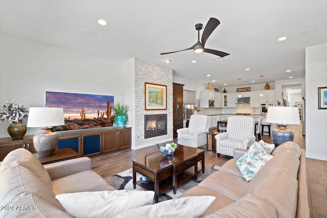 living room with ceiling fan and a fireplace