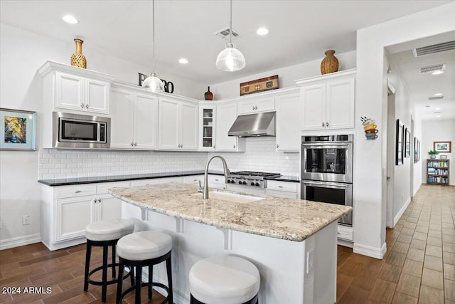 kitchen featuring white cabinetry, pendant lighting, exhaust hood, and appliances with stainless steel finishes