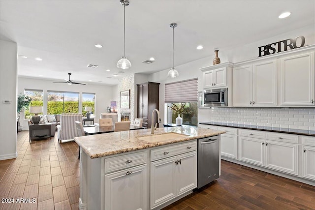 kitchen featuring appliances with stainless steel finishes, sink, dark stone countertops, white cabinetry, and hanging light fixtures