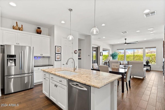 kitchen featuring appliances with stainless steel finishes, tasteful backsplash, sink, white cabinetry, and hanging light fixtures