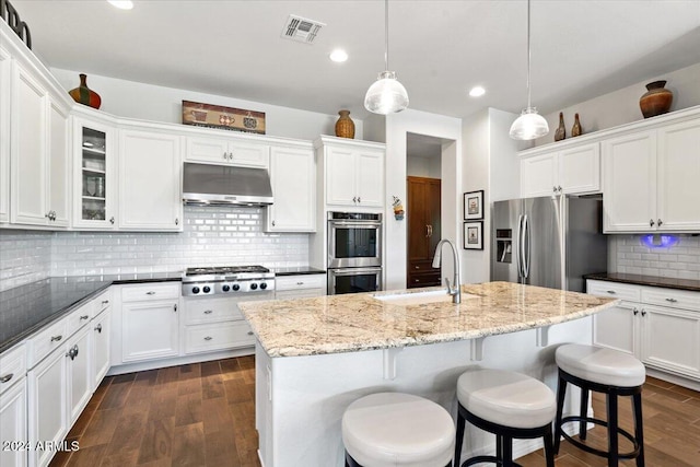 kitchen featuring decorative backsplash, stainless steel appliances, a kitchen island with sink, sink, and decorative light fixtures