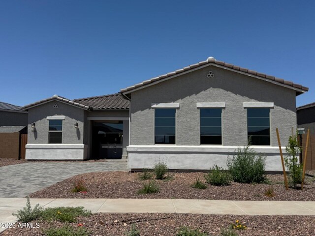 view of front of property featuring stucco siding, fence private yard, and a tile roof