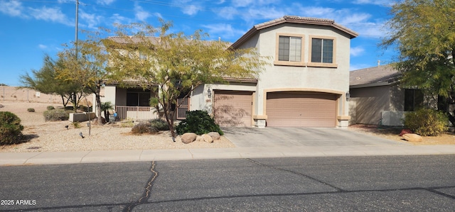 view of front of home with stucco siding, a tile roof, a porch, concrete driveway, and an attached garage