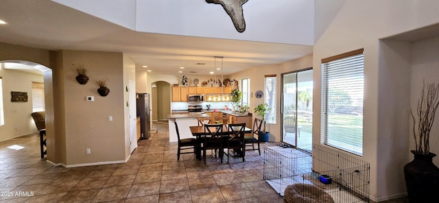 tiled dining area featuring recessed lighting, baseboards, and arched walkways