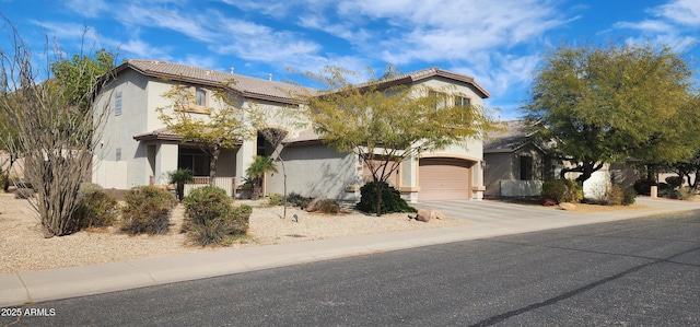 view of front of house with stucco siding, driveway, a tile roof, and a garage