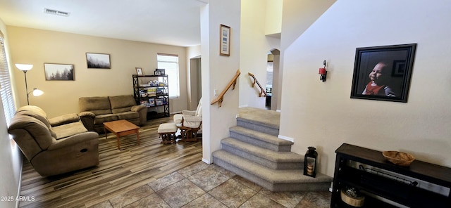 living area with arched walkways, visible vents, stairway, and wood finished floors