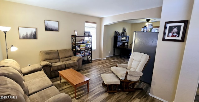 living area with arched walkways, baseboards, and wood finished floors