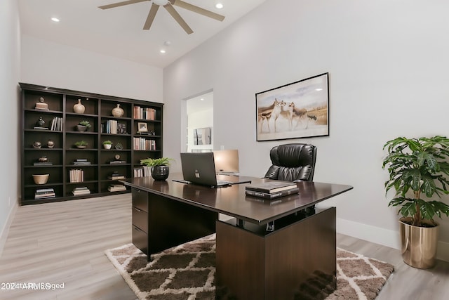 home office featuring light wood-type flooring, a high ceiling, and ceiling fan