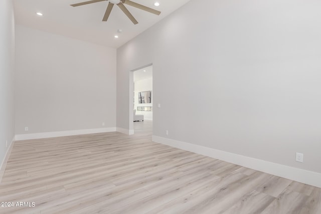 spare room with light wood-type flooring, a high ceiling, and ceiling fan