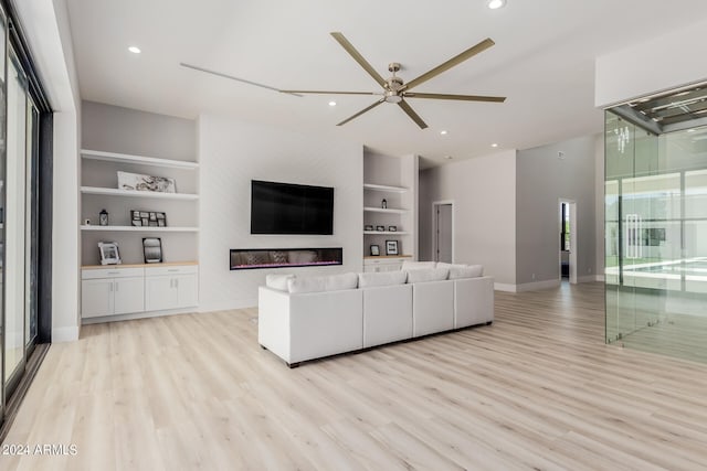 unfurnished living room with light hardwood / wood-style floors, ceiling fan, and built in shelves