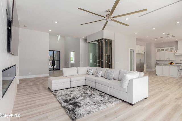 living room with ceiling fan, light hardwood / wood-style flooring, and sink