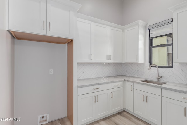 kitchen featuring white cabinetry, light hardwood / wood-style floors, light stone counters, and sink