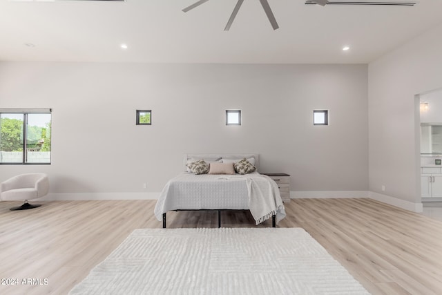 bedroom with connected bathroom, light hardwood / wood-style floors, and ceiling fan