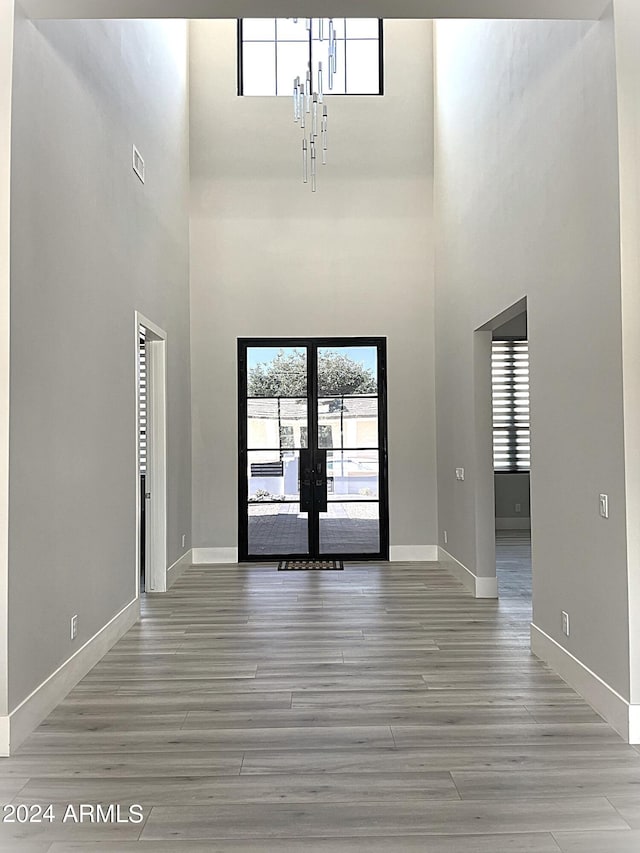 entrance foyer featuring french doors, light hardwood / wood-style flooring, and a towering ceiling