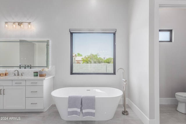 bathroom featuring vanity, a tub to relax in, and toilet