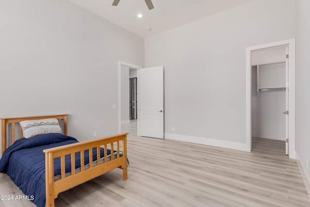 bedroom featuring a closet, light hardwood / wood-style floors, ceiling fan, and a walk in closet