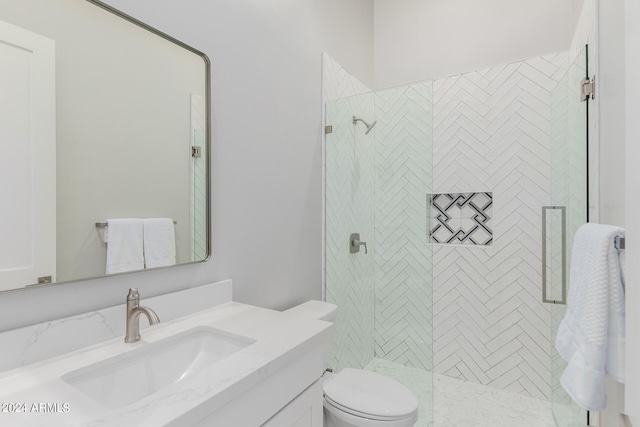 bathroom with a tile shower, vanity, and toilet