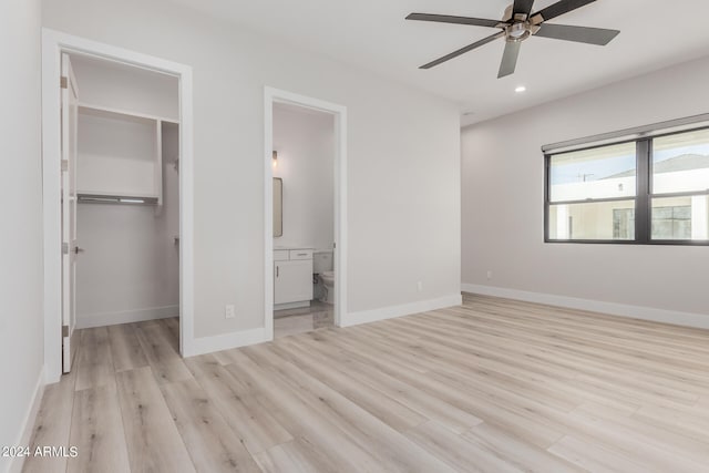 unfurnished bedroom with ceiling fan, connected bathroom, light hardwood / wood-style flooring, a closet, and a spacious closet