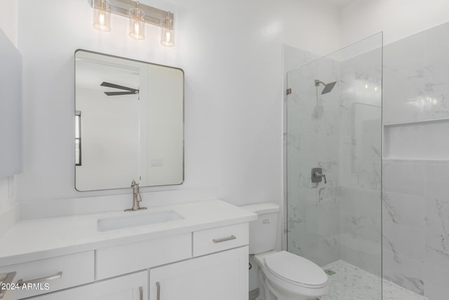 bathroom featuring a tile shower, ceiling fan, vanity, and toilet