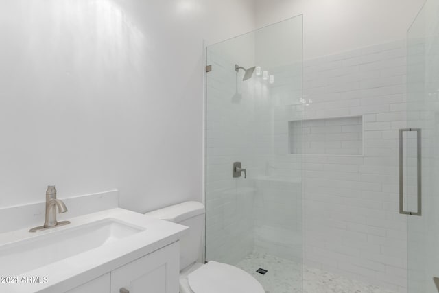 bathroom featuring vanity, a shower with shower door, and toilet