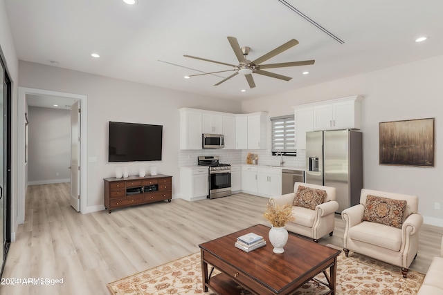 living room with light wood-type flooring, ceiling fan, and sink