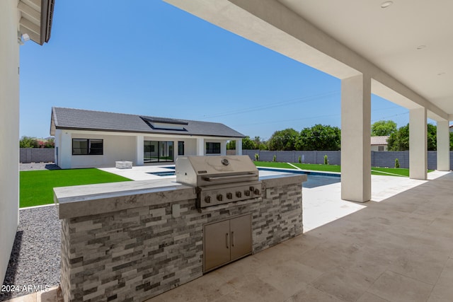 view of patio with a grill, a fenced in pool, and an outdoor kitchen