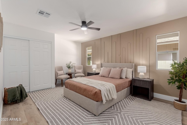 bedroom featuring ceiling fan, a closet, multiple windows, and light hardwood / wood-style flooring