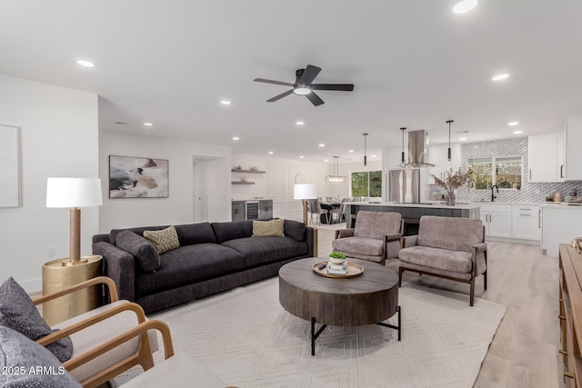 living room with sink, light hardwood / wood-style floors, and ceiling fan