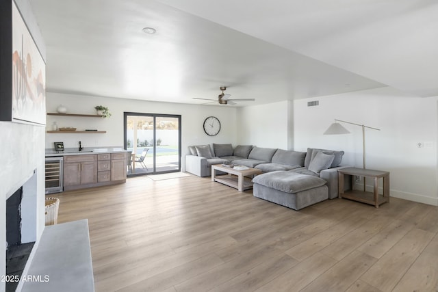 living room featuring wine cooler, ceiling fan, and light hardwood / wood-style floors