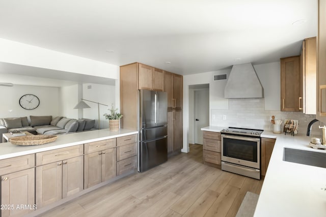 kitchen with stainless steel appliances, tasteful backsplash, sink, light wood-type flooring, and custom range hood