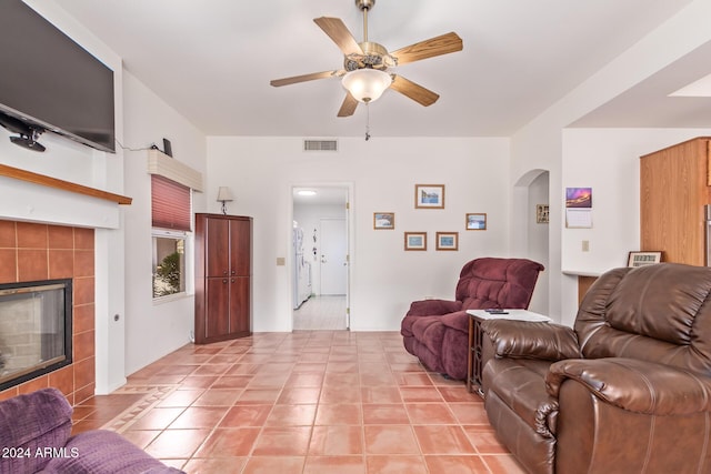 tiled living room featuring a tiled fireplace and ceiling fan