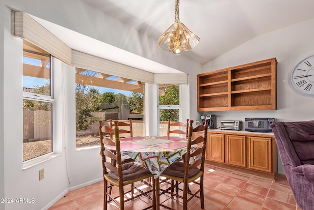 dining room with light tile patterned floors, lofted ceiling, a healthy amount of sunlight, and a notable chandelier