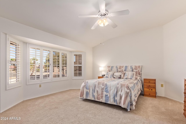 bedroom with ceiling fan, light colored carpet, and vaulted ceiling