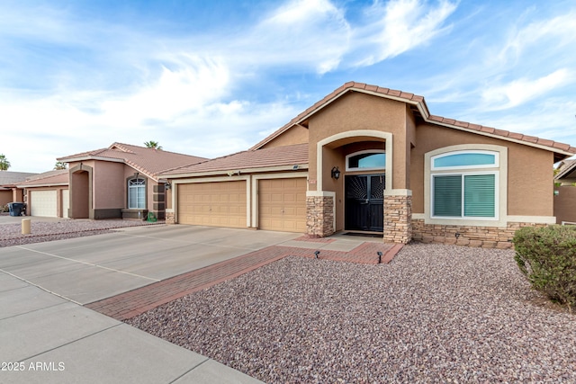 view of front of house with stucco siding, a garage, stone siding, driveway, and a tiled roof