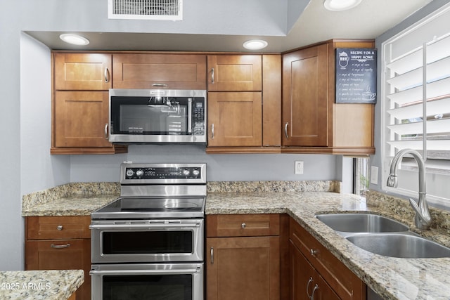 5755 W Harrison St, Chandler, AZ 85226 - kitchen featuring visible vents, light stone countertops, brown cabinets, appliances with stainless steel finishes, and a sink