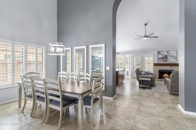 5755 W Harrison St, Chandler, AZ 85226 - dining area featuring baseboards, a warm lit fireplace, a towering ceiling, arched walkways, and a ceiling fan