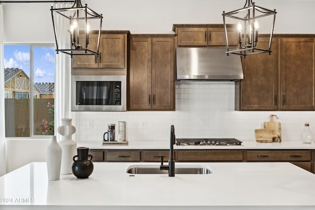 kitchen featuring backsplash, sink, exhaust hood, and appliances with stainless steel finishes