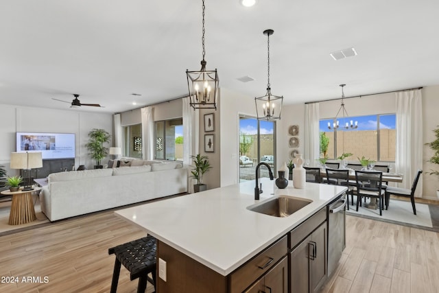 kitchen featuring dishwasher, a center island with sink, sink, light hardwood / wood-style flooring, and ceiling fan