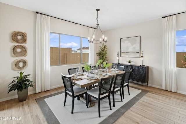 dining space with light hardwood / wood-style floors and an inviting chandelier