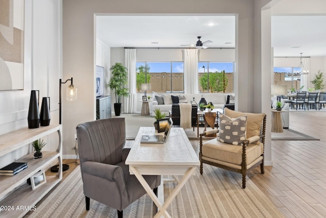 interior space with ceiling fan with notable chandelier and light hardwood / wood-style flooring